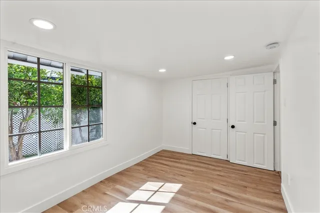 a view of empty room with wooden floor and fan