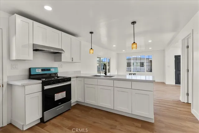 a kitchen with stainless steel appliances granite countertop a sink a stove and a wooden floors