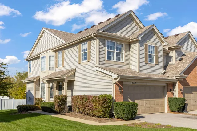 a view of a white house next to a yard with potted plants