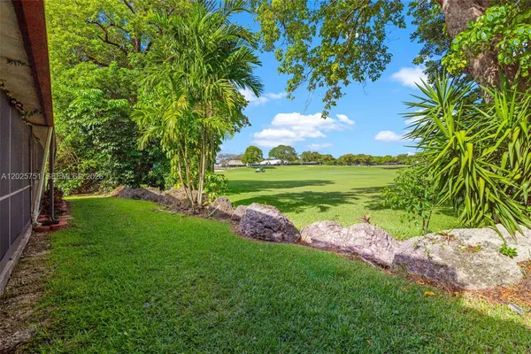 a view of a big yard with plants and large trees