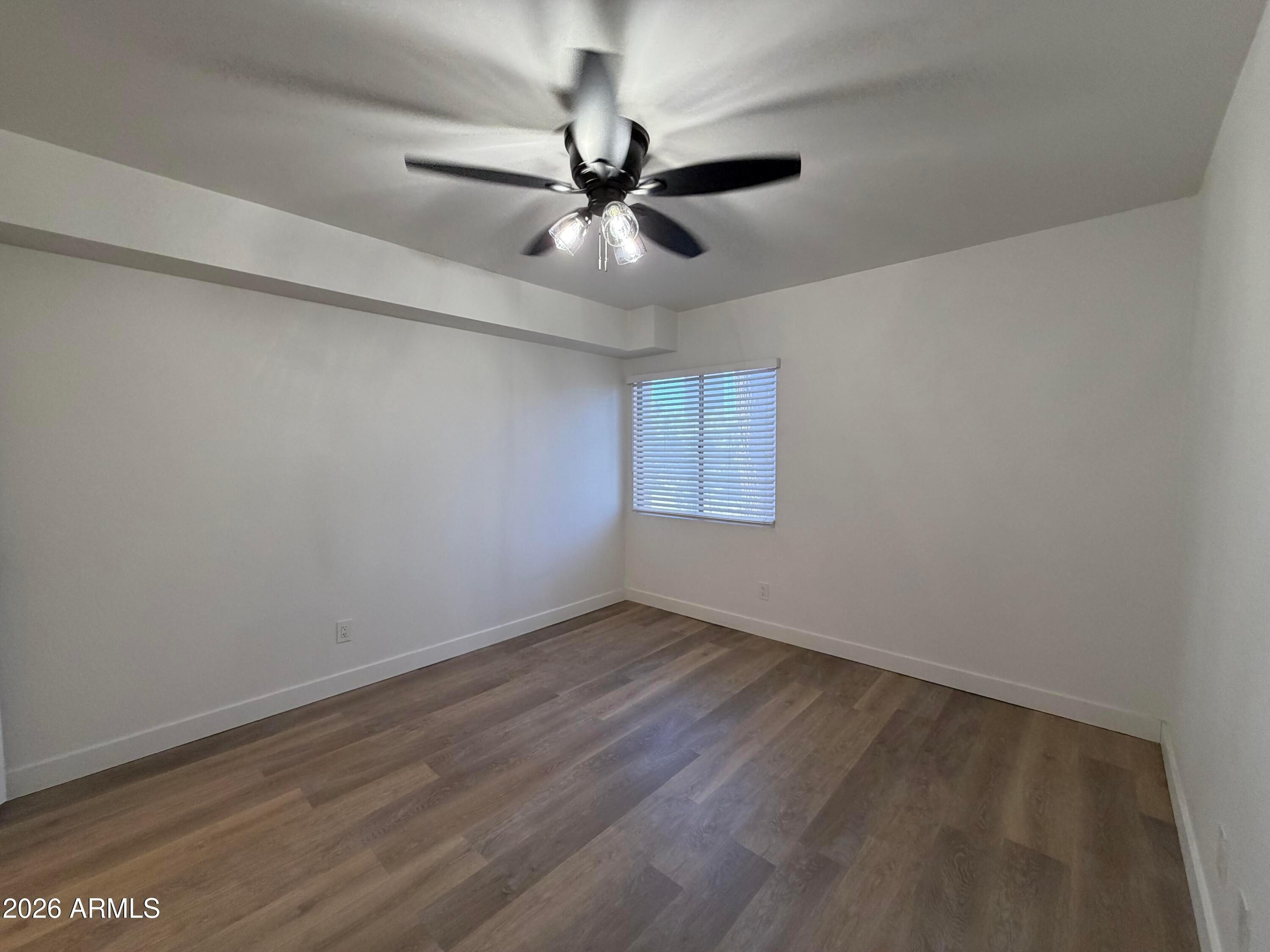 302 East Monte Vista Road, Unit A5 Phoenix, AZ 85004 - Photo 12 of 23 an empty room with wooden floor fan and windows