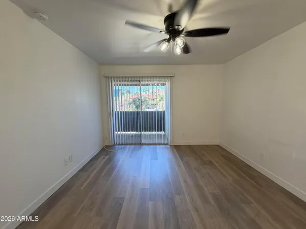 an empty room with wooden floor chandelier fan and windows