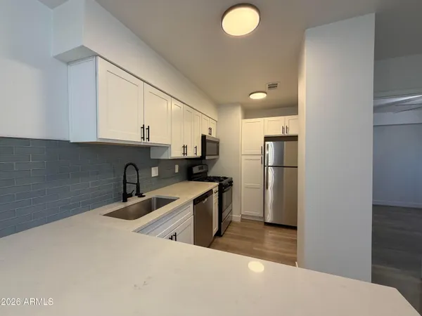 a kitchen with stainless steel appliances granite countertop a sink a refrigerator and a stove