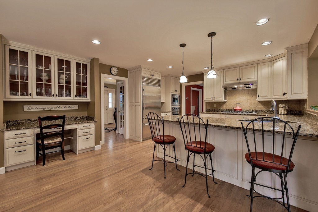 25 Chandler Road Boxford, MA 01921 - Photo 9 of 30 a kitchen with stainless steel appliances granite countertop a stove top oven a refrigerator a dining table and chairs with wooden floor