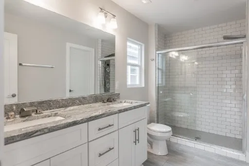 a bathroom with a granite countertop sink a toilet and shower