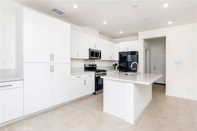 a kitchen with a sink a stove top oven and white stainless steel appliances