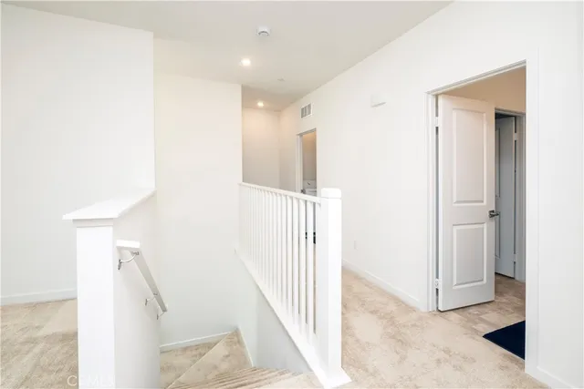a view of a hallway with white walls and stairs