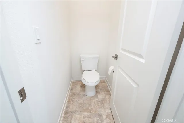 a white toilet sitting next to a white wall
