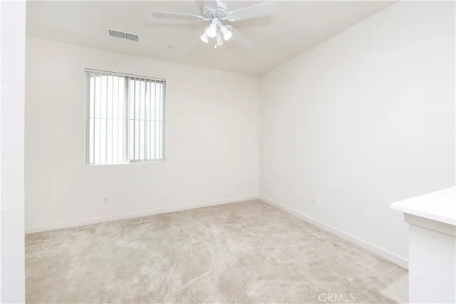 an empty room with a window and a ceiling fan
