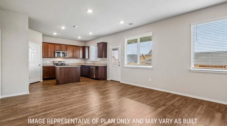 10101 Altair Drive Waco, TX 76708 - Photo 11 of 36 Wood-finish flooring throughout, recessed lighting, and a kitchen featuring dark wood cabinetry, a center island, and stainless steel appliances
