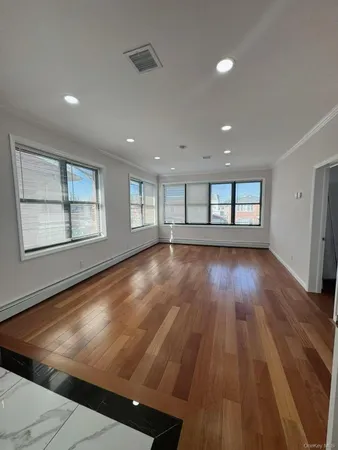 a view of an empty room with wooden floor and fan