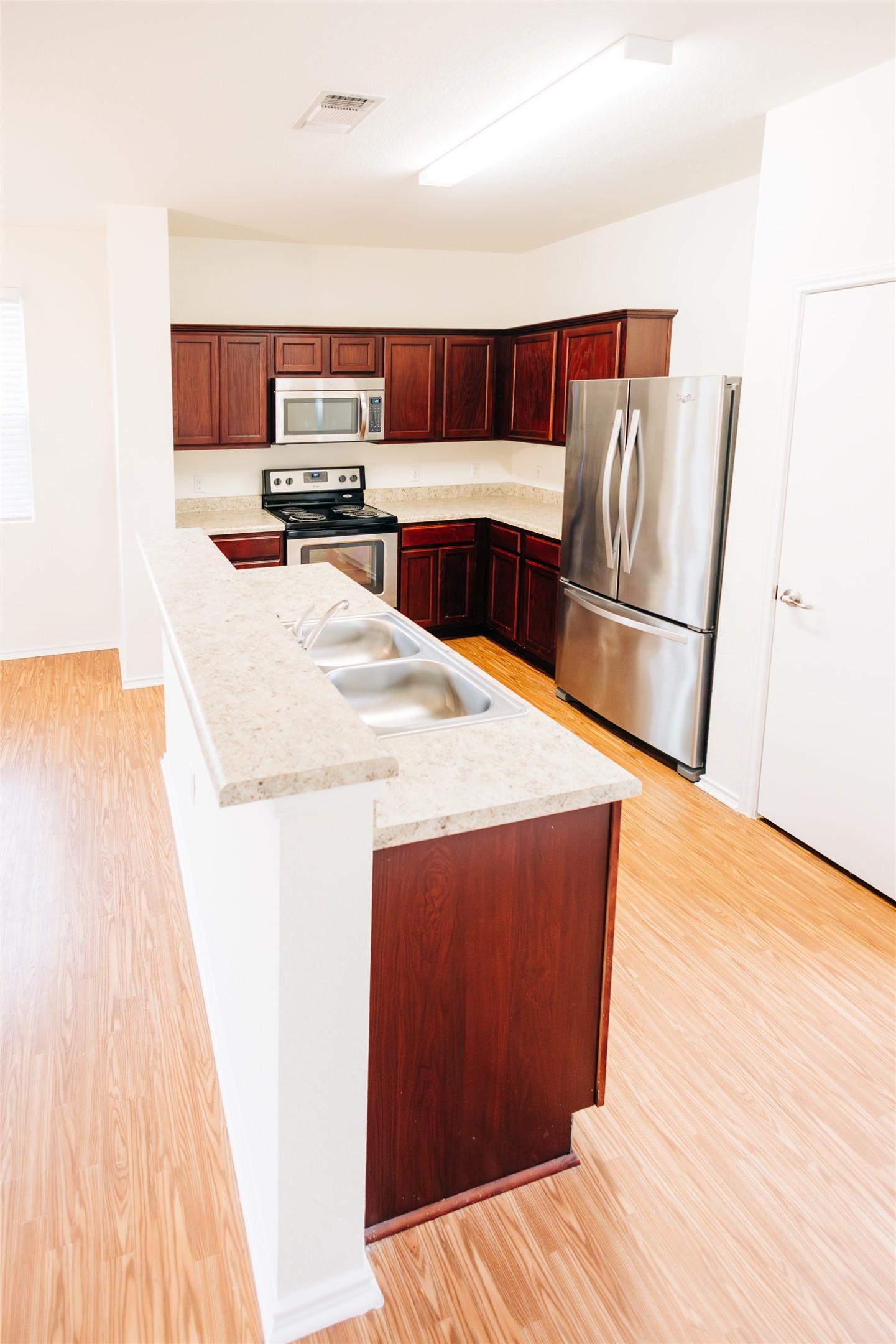 2905 Acopio Bend Austin, TX 78745 - Photo 8 of 29 Kitchen featuring stainless steel appliances, light countertops, light wood-style flooring, an island with sink, and bold wood finish cabinetry