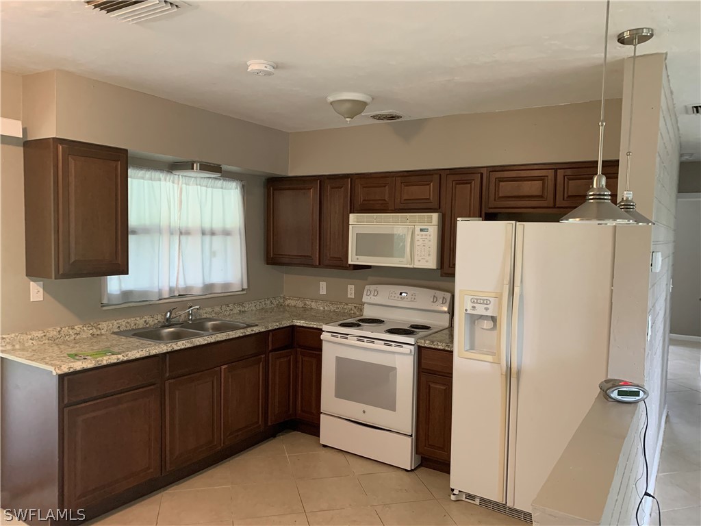 2819 W Road Fort Myers, FL 33905 - Photo 4 of 12 a kitchen with a sink a stove a refrigerator and cabinets