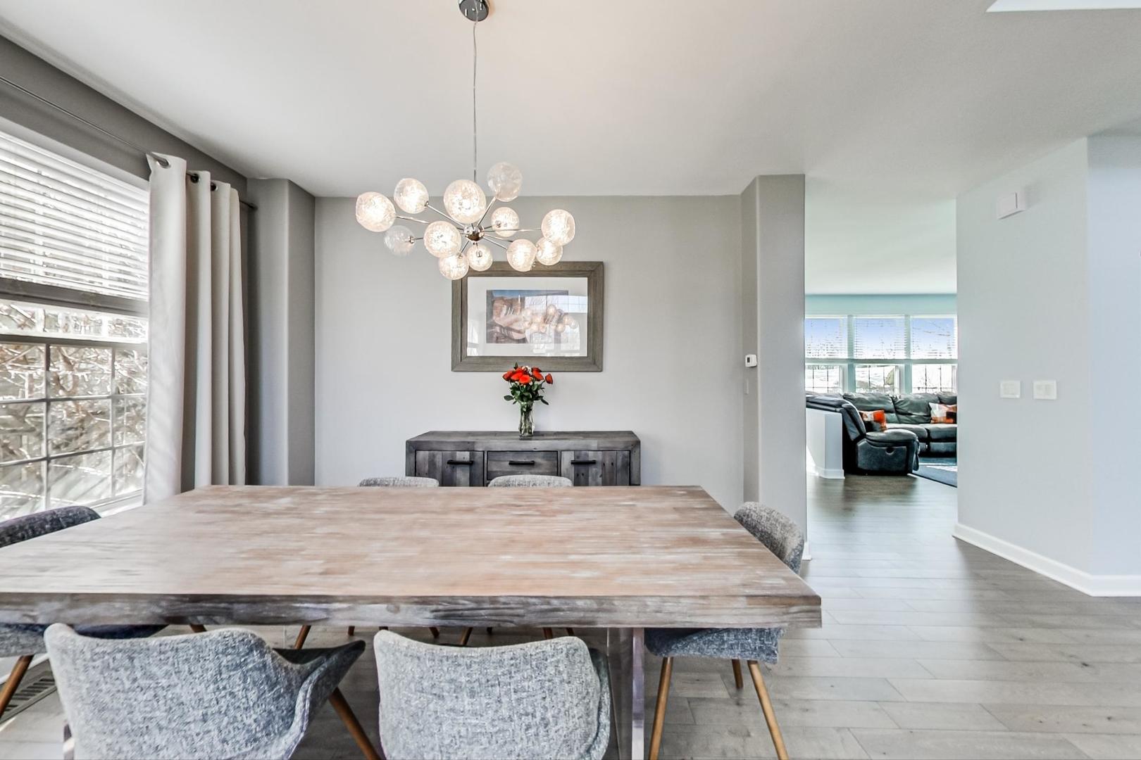 7311 Dada Drive Gurnee, IL 60031 - Photo 8 of 51 a dining room with wooden floor a chandelier a wooden table and chairs