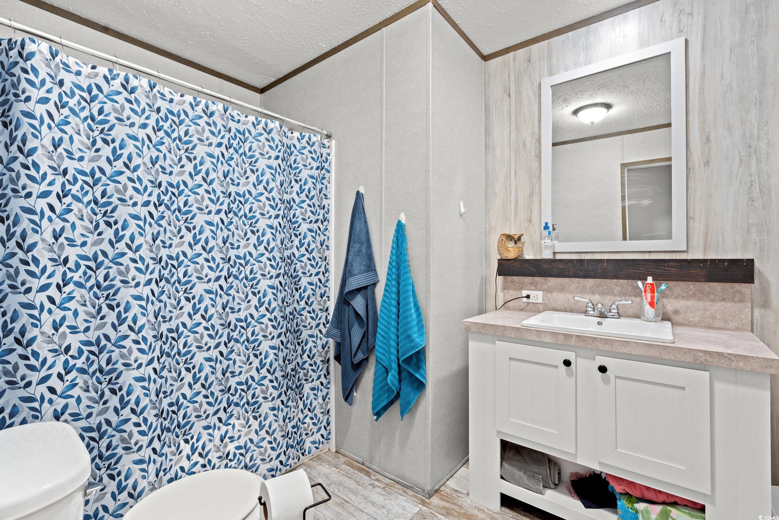 1217 Poplar Creek Road Lake View, SC 29563 - Photo 23 of 38 Full bathroom with a textured ceiling, vanity, light wood finished floors, a shower with curtain, and crown molding