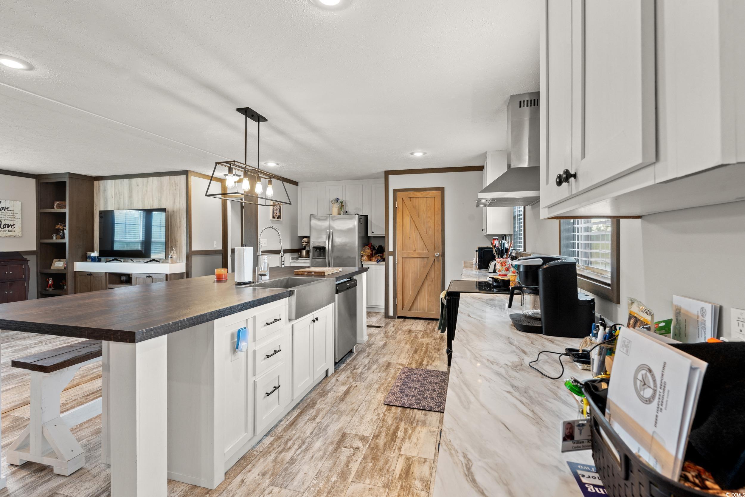 1217 Poplar Creek Road Lake View, SC 29563 - Photo 10 of 38 Kitchen with white cabinetry, a kitchen island with sink, hanging light fixtures, recessed lighting, and wall chimney range hood