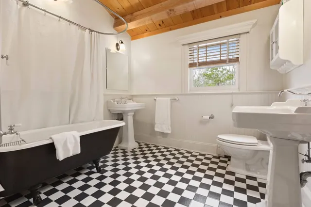 a bathroom with a sink a toilet a window and shower