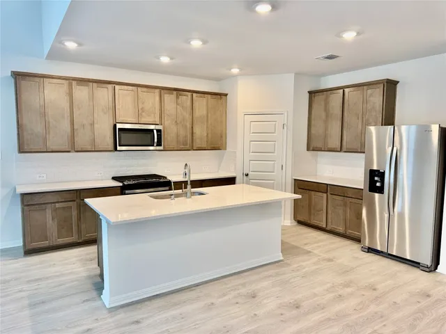a large kitchen with a stove a sink and a microwave