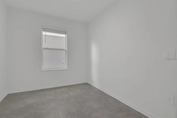 a view of an empty room with closet and a window