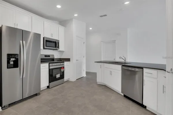 a kitchen with granite countertop a sink and white cabinets