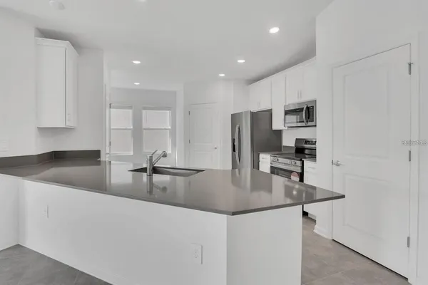 a kitchen with granite countertop a stove a sink and a refrigerator