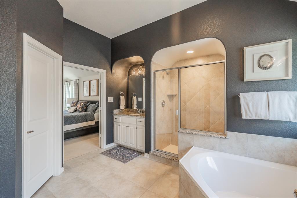 1205 Ivy Charm Way Arlington, TX 76005 - Photo 25 of 40 Archway entry shower with glass enclosure, separate soaking tub, single vanity with light-tone countertop, and tile flooring