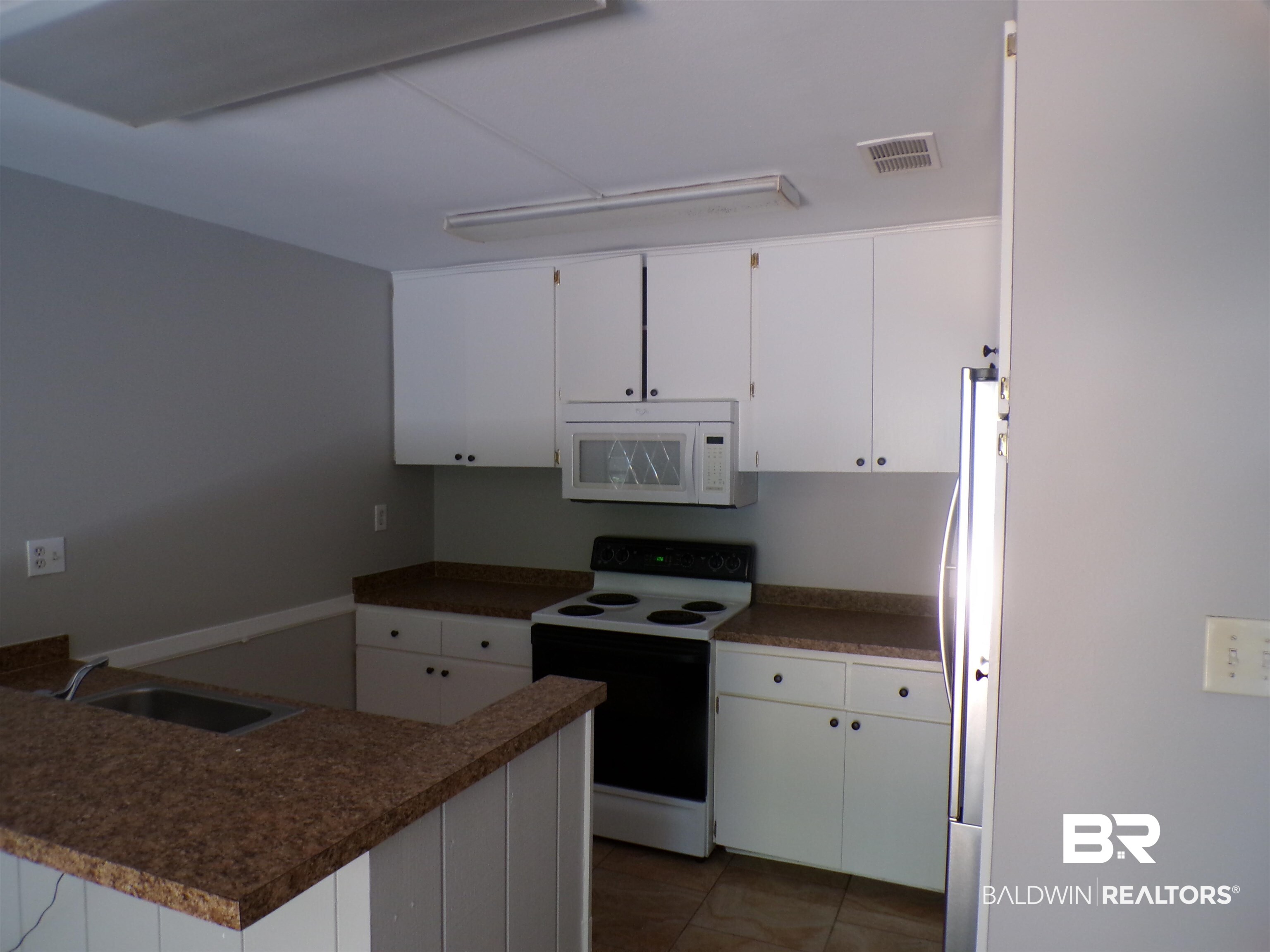 1152 North Alston Street, Unit 1152 Foley, AL 36535 - Photo 5 of 16 Kitchen featuring white cabinetry, speckled countertops, a built-in microwave, an electric range, and tile flooring