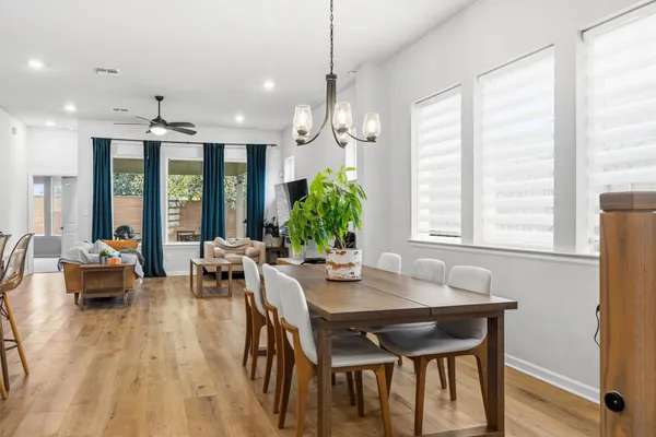 a dining room with wooden floor a chandelier a glass table and chairs