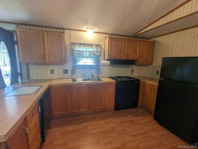 a kitchen with a sink a stove a refrigerator a window and cabinets