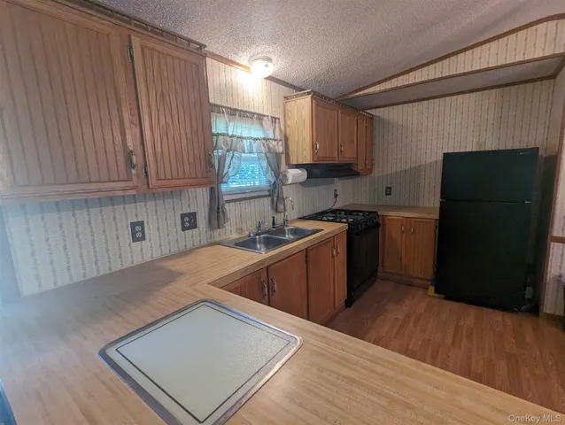 a kitchen with stainless steel appliances granite countertop a refrigerator a sink dishwasher a stove and white countertops with wooden floor