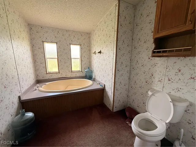 a bathroom with a granite countertop toilet sink and mirror