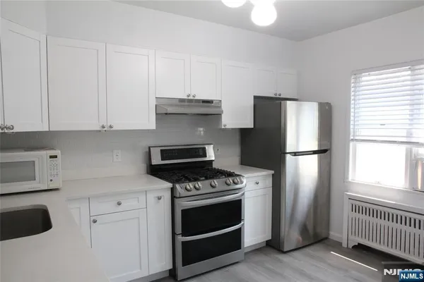 a kitchen with refrigerator a stove a sink and cabinets