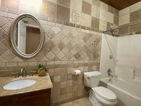 a bathroom with a granite countertop sink mirror vanity and toilet