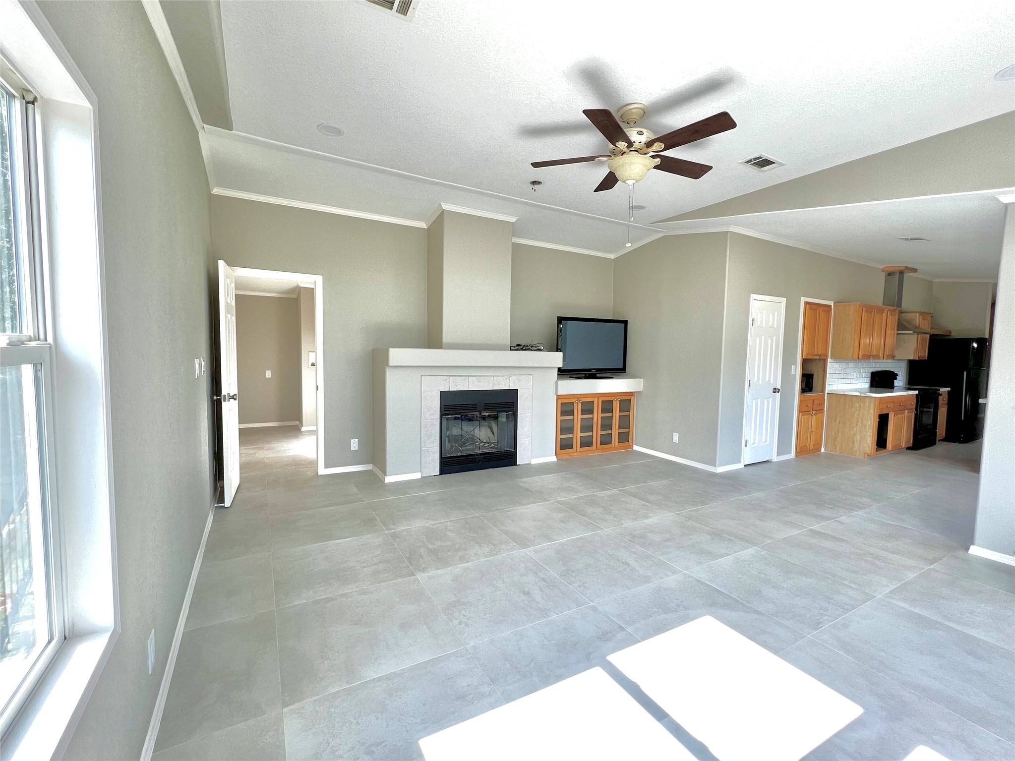 14505 Alice Road Tomball, TX 77377 - Photo 11 of 28 a view of a livingroom with a fireplace a ceiling fan a kitchen space a sink and a window