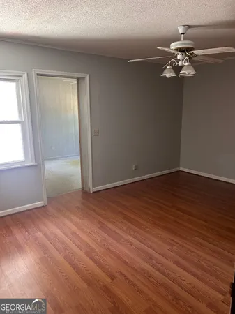 an empty room with wooden floor and windows