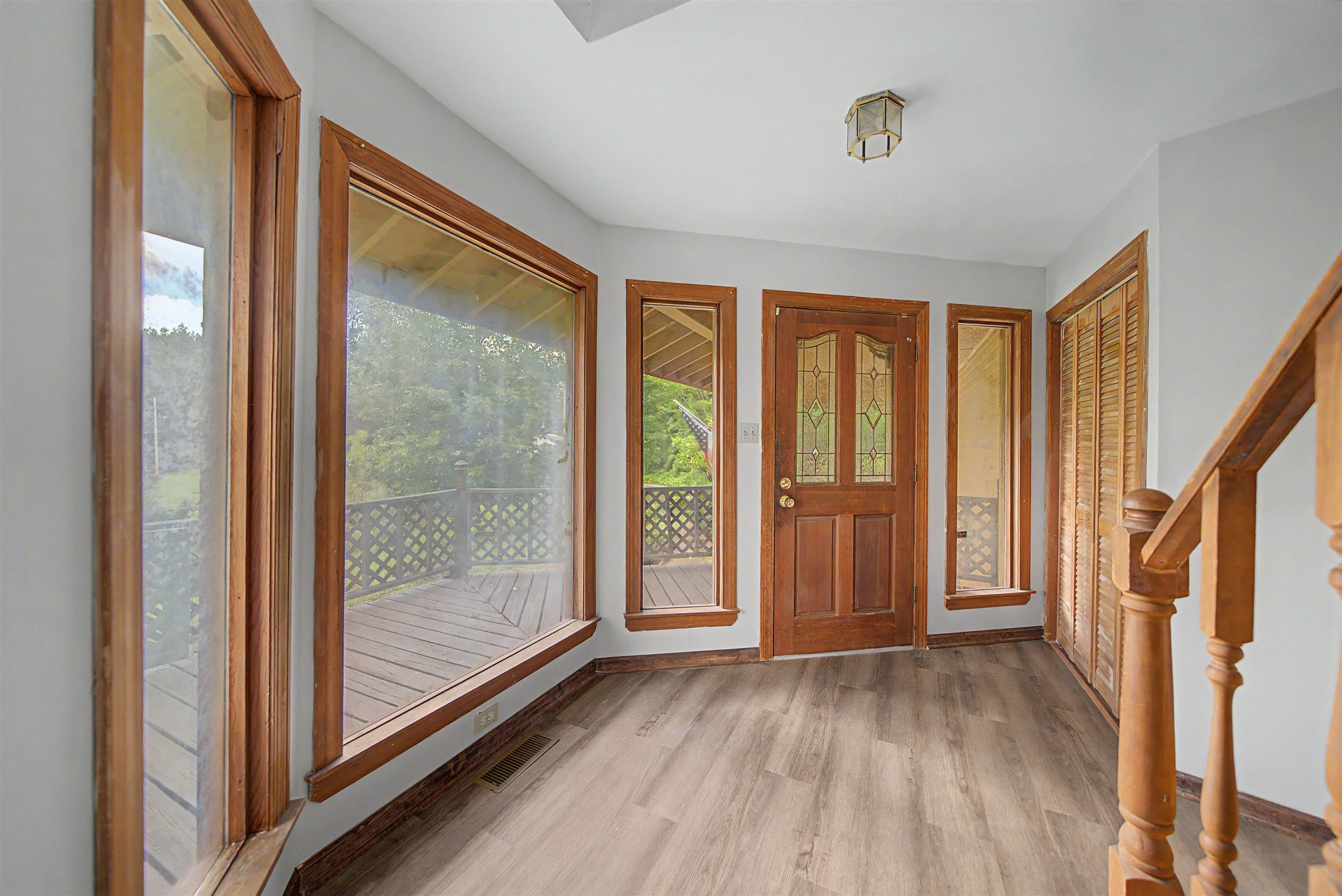 2380 Dunaway Road Selmer, TN 38375 - Photo 14 of 39 Entryway featuring wood-finish flooring, a decorative wood entry door with glass inserts, and multiple large windows with wood trim