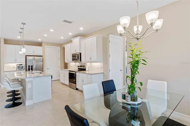 a large kitchen with kitchen island granite countertop a stove a sink a dining table and chairs with wooden floor