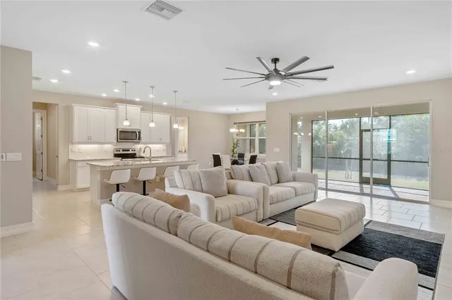 a living room with furniture and a large window with kitchen view