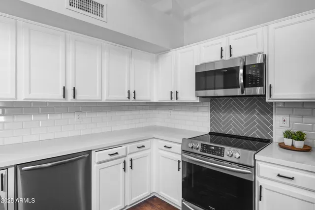 a kitchen with stainless steel appliances granite countertop a sink stove a refrigerator and cabinets