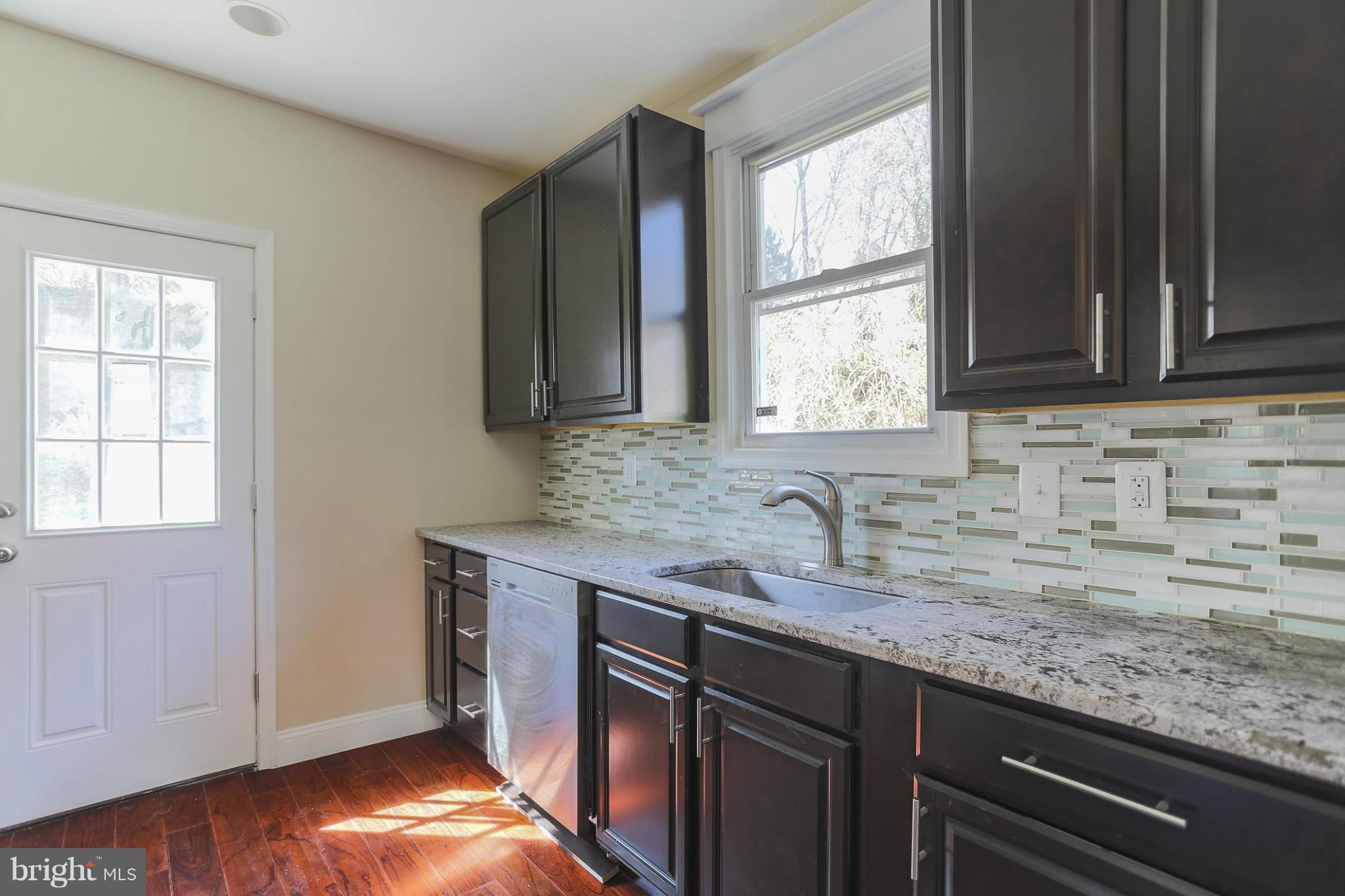 2304 Monticello Road Baltimore, MD 21216 - Photo 13 of 30 a kitchen with granite countertop wooden cabinets a sink and a window