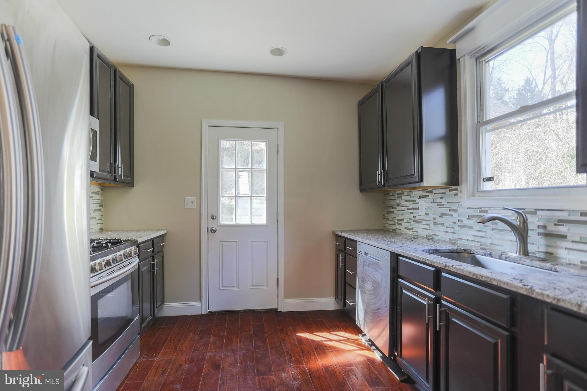 2304 Monticello Road Baltimore, MD 21216 - Photo 3 of 30 a kitchen with granite countertop a sink cabinets stainless steel appliances and a window