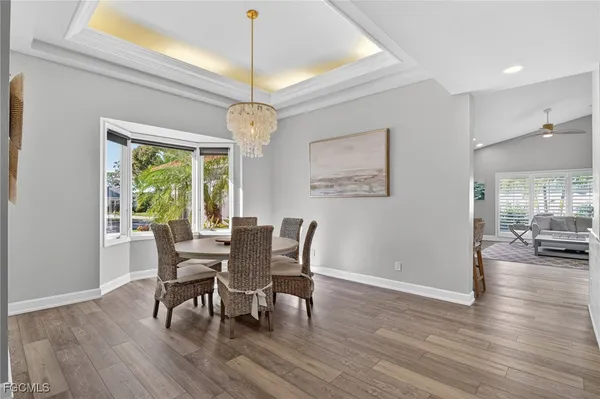 a dining room with wooden floor a chandelier a wooden table and chairs