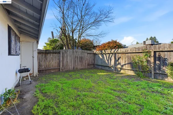 a view of backyard with wooden fence and a bench