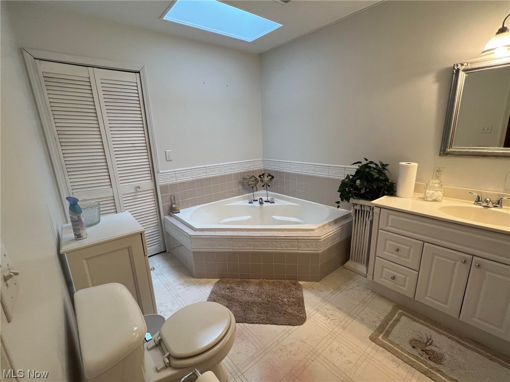 36555 Flat Rock Road Barnesville, OH 43713 - Photo 15 of 35 Bathroom featuring vanity, tiled bath, toilet, tile floors, and a skylight