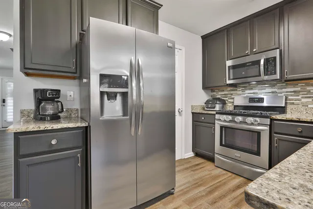 a kitchen with stainless steel appliances granite countertop a refrigerator stove and sink