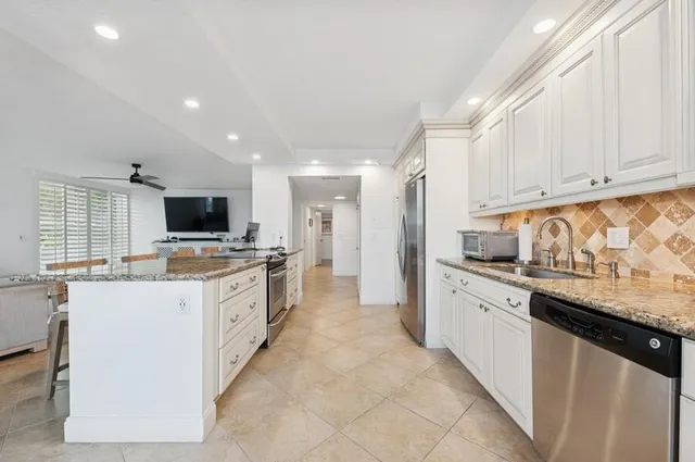 a large kitchen with stainless steel appliances kitchen island granite countertop a stove and a sink