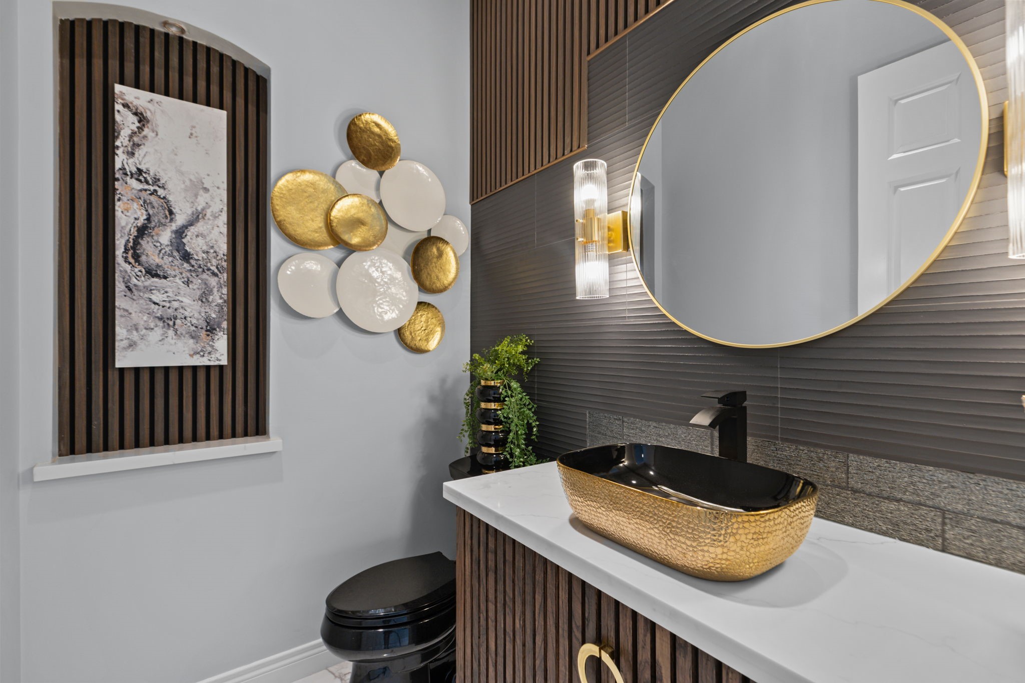 39 Maymont Way Spring, TX 77382 - Photo 19 of 50 This bathroom features a modern design with textured walls, a stylish black and gold sink, and a large circular mirror. Artistic wall decor and sleek lighting add elegance to the space.
