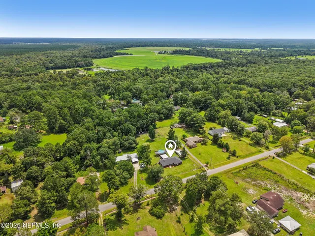 an aerial view of residential houses with outdoor space and trees