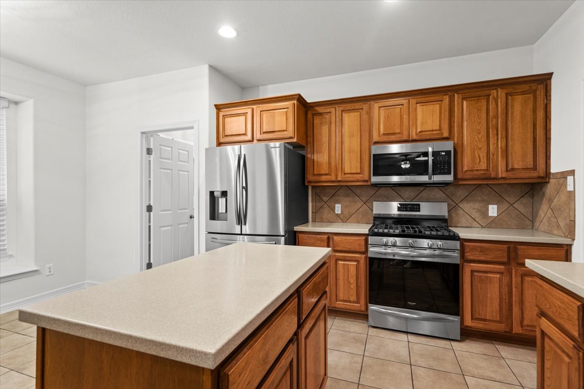 2304 Village View Loop Pflugerville, TX 78660 - Photo 9 of 40 A warm-toned kitchen with stainless steel appliances and light countertops, perfect for culinary adventures.