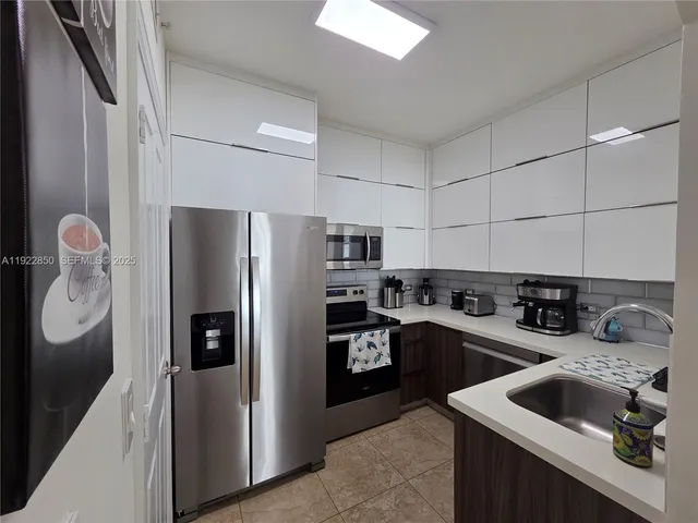 a kitchen with stainless steel appliances granite countertop a refrigerator a sink a stove and a refrigerator